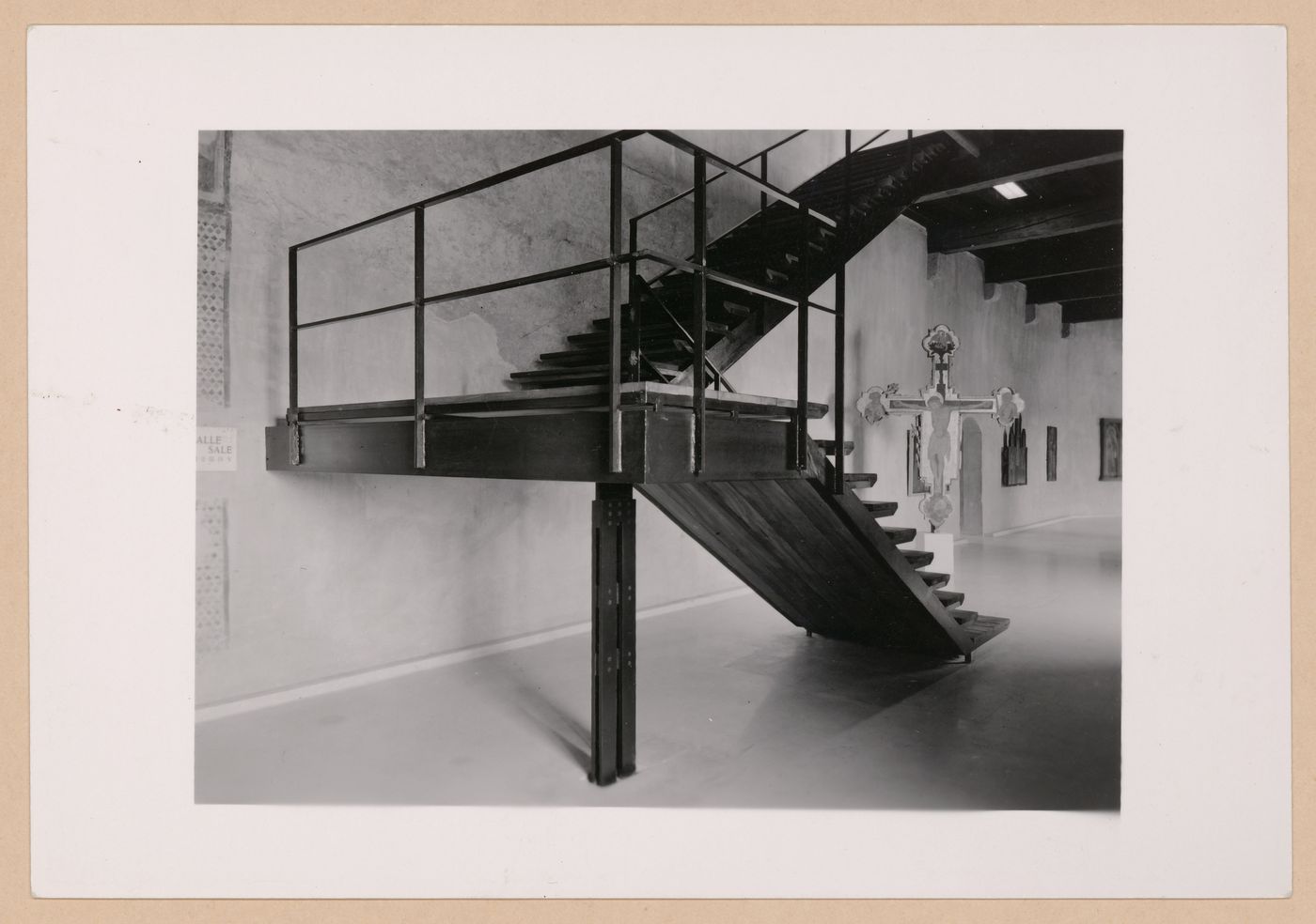 Interior view of a gallery showing a staircase with a freestanding painted crucifix and paintings in the background, Museo di Castelvecchio, Verona, Italy