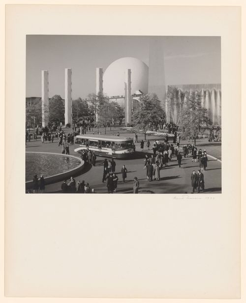 New York World's Fair (1939-1940): Crowds and bus in plaza with pool on left, 4 pylons, Perisphere and Trylon in background