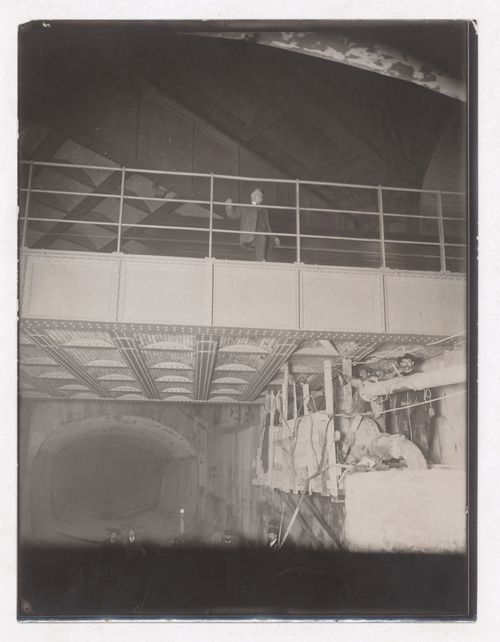 Construction of the Paris Metro, interior view with man standing near walkway railing with workers working underneath, Paris, France