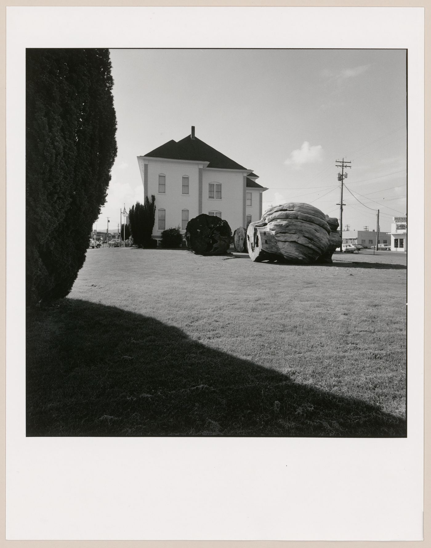Side view of the Tillamook County Pioneer Museum (formerly the Tillamook County Courthouse) with sections of  cut-down cedar tree in yard, 2106 2nd Street, Tillamook, Oregon, United States