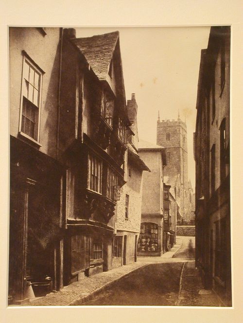 View of houses in a narrow street, with a church tower at the end, Dartmouth, England