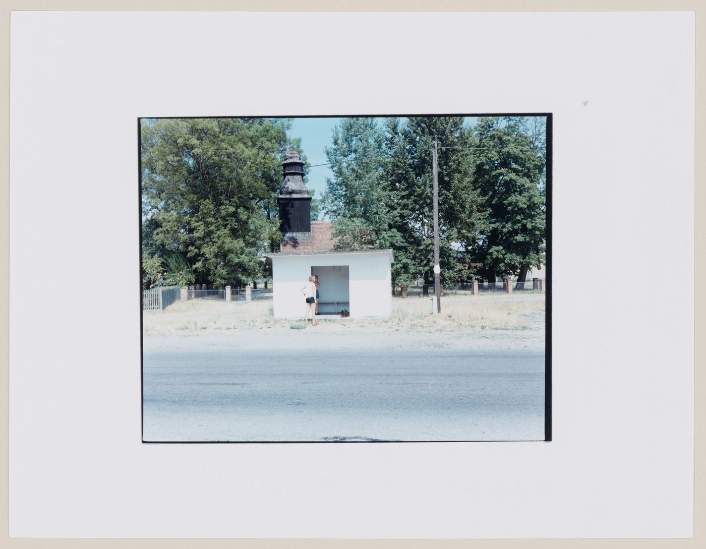 View of a bus shelter, a church tower, a road and people, Strzelce Kraje'nskie, Poland (from the series "In between cities")