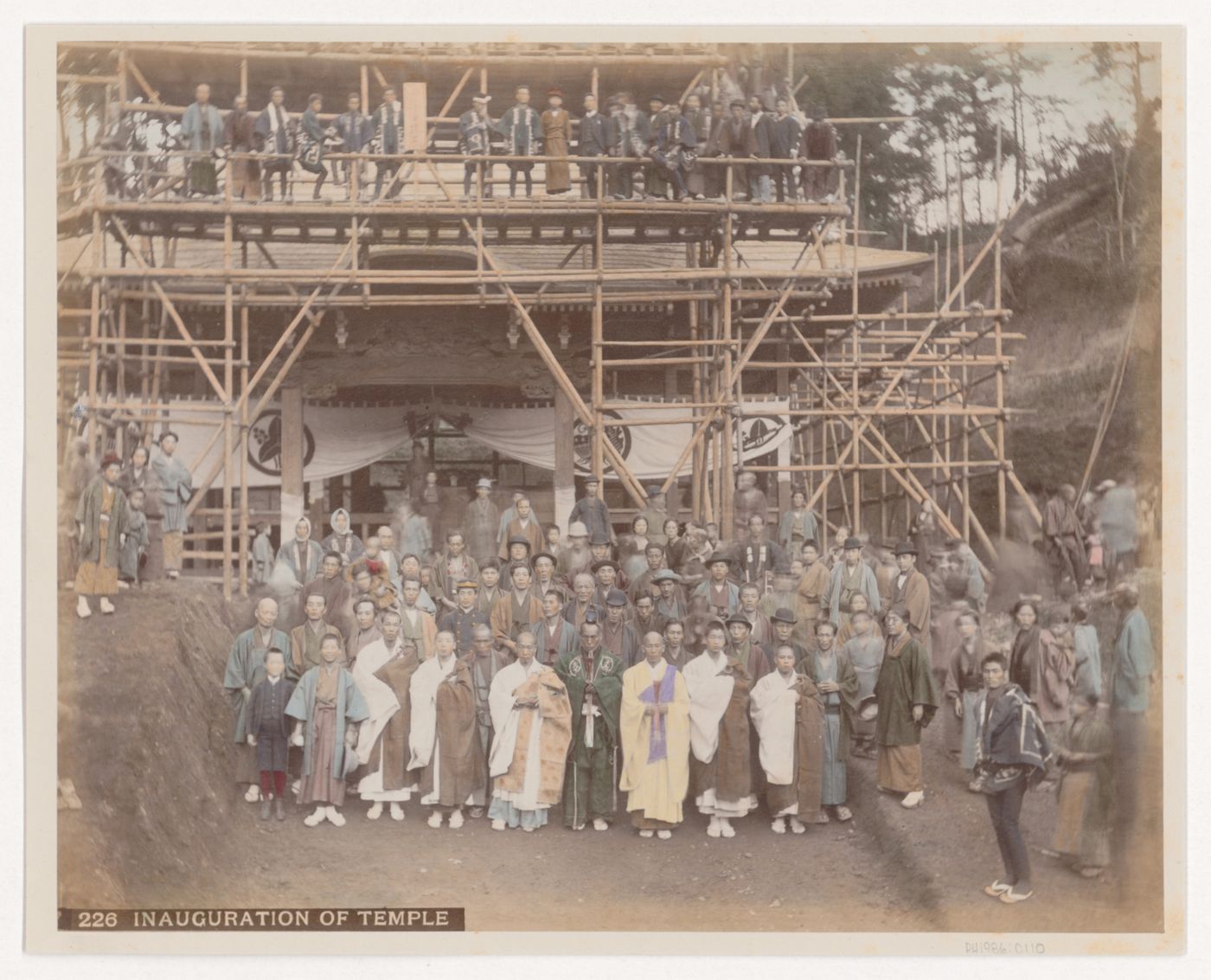Group portrait of people in front of a newly inaugurated shrine or temple with scaffolding, Japan