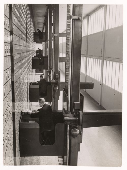 Interior view of the Central Social Insurance Institution showing men working in mobile work stations used to access the card catalog drawers, Prague, Czechoslovakia (now Czech Republic)