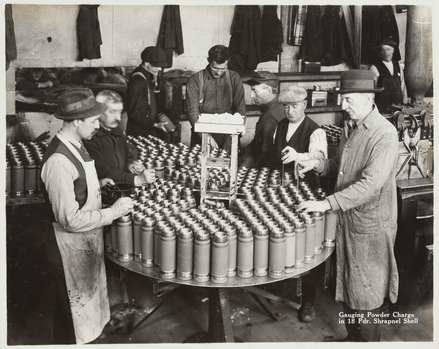 Interior view of workers gauging powder charge in shrapnel shell at the Energite Explosives Plant No. 3, the Shell Loading Plant, Renfrew, Ontario, Canada