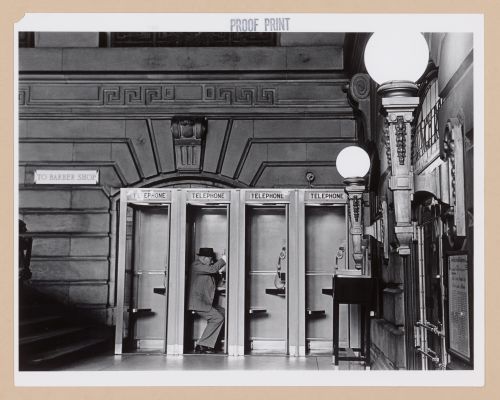 Interior view of the Lackawanna Railroad Terminal showing telephone booths and a man, Hoboken