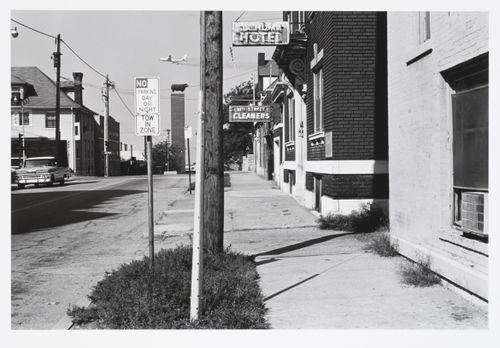 Street view with a monument of a bull, and a plane flying over it at the end of the street, Kansas City, Missouri