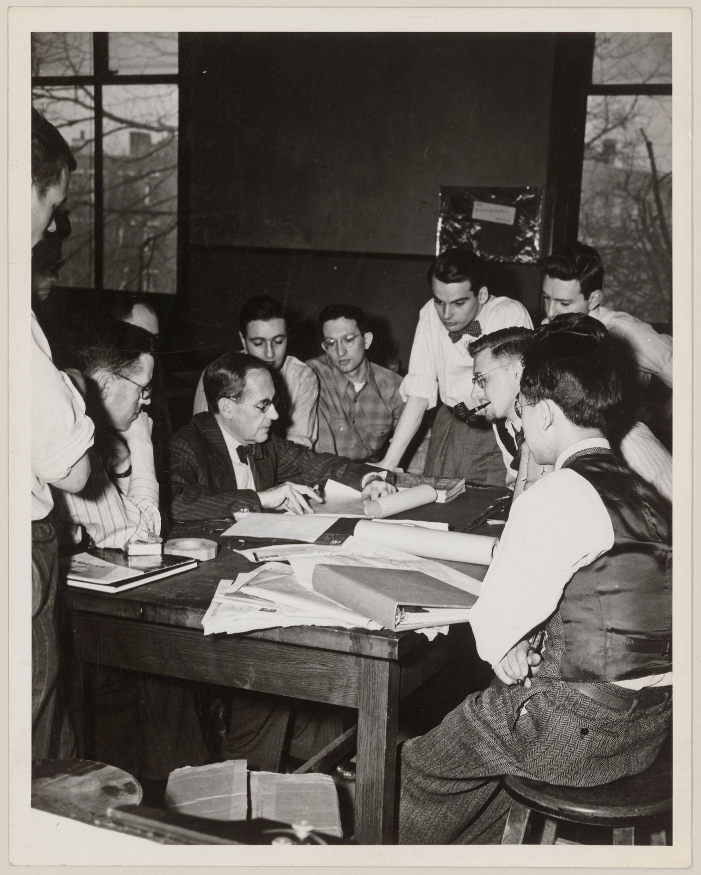 Walter Gropius with Parkin and other students gathered around drawings on table, possibly at Harvard