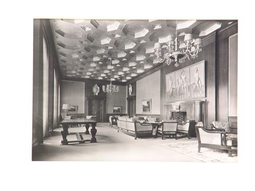 Interior of large room, with coffered ceiling and painted triptych above fireplace