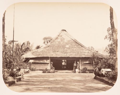 View of a thatched roof building and statues, near Borobudur, Dutch East Indies (now Indonesia)
