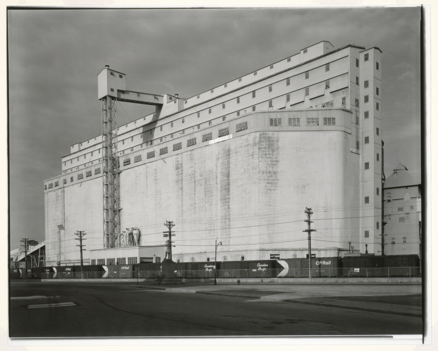 View of Grain Elevator No. 1 (now demolished) showing railway cars and a monument in the foreground, Port of Montréal, Québec