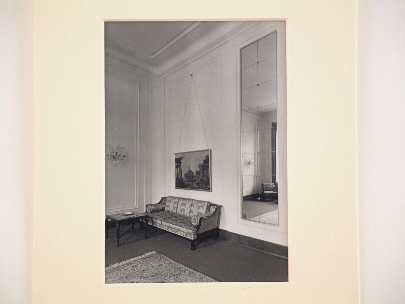 Corner of large room with painting above couch, and large mirrored panel