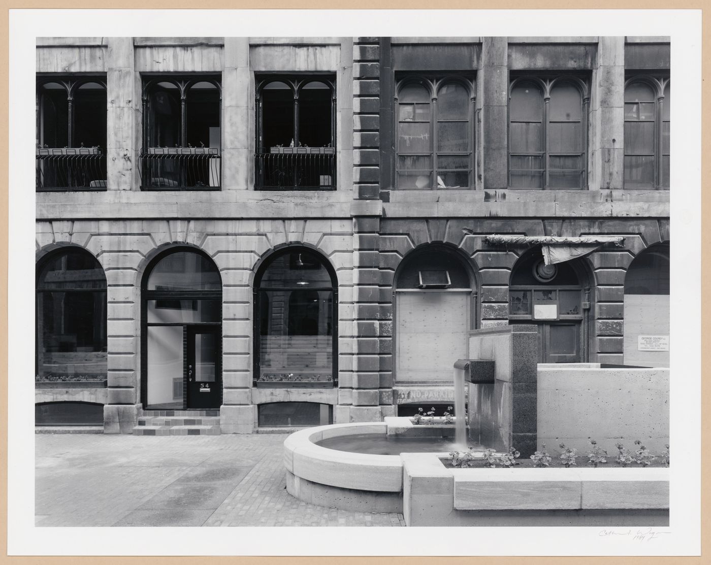 Partial view of the principal façade of Cours Le Royer with a fountain in the foreground, Montréal, Québec