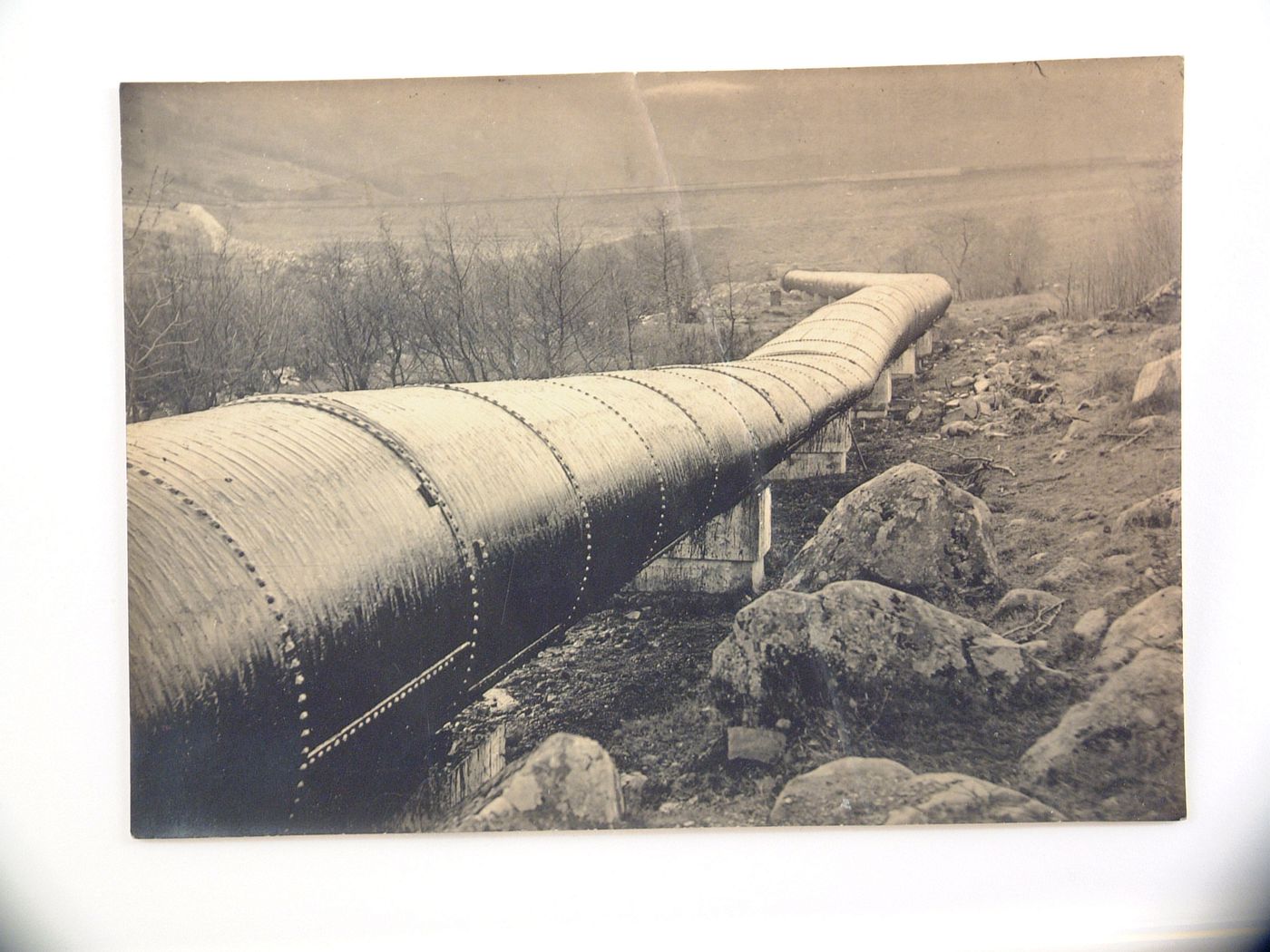 View of large riveted pipeline, unknown location