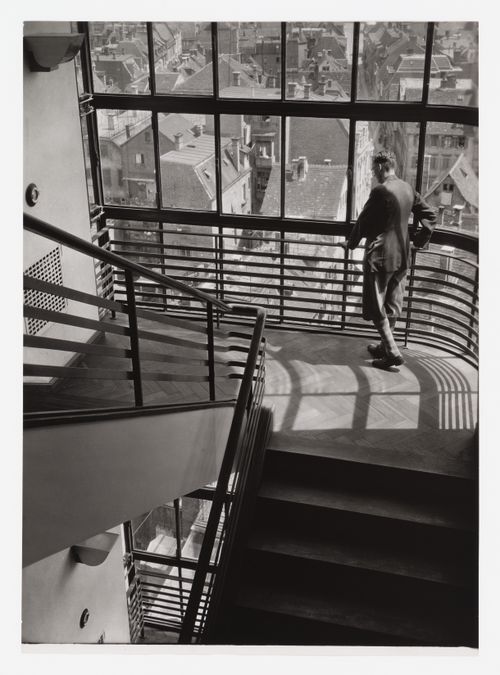 Interior of Kaufhaus Breminger detail of stairwell, with man in knickerbockers at railing, and view of roofs and town, Germany