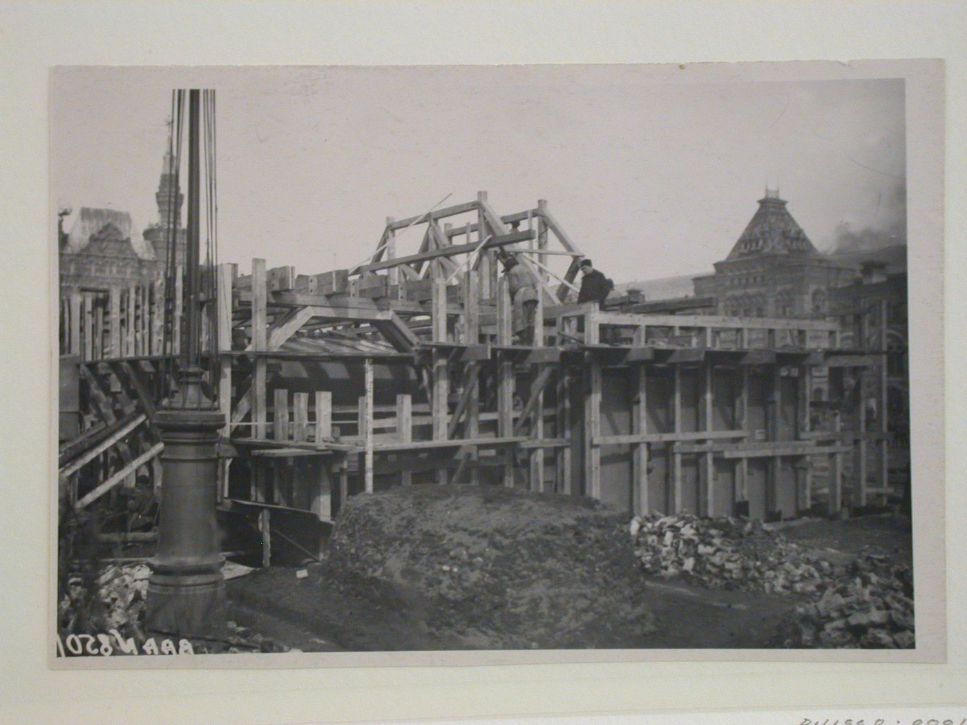 View of the lateral façade of the second wooden Lenin Mausoleum under construction showing the Upper Shopping Arcades on the far right, Red Square, Moscow