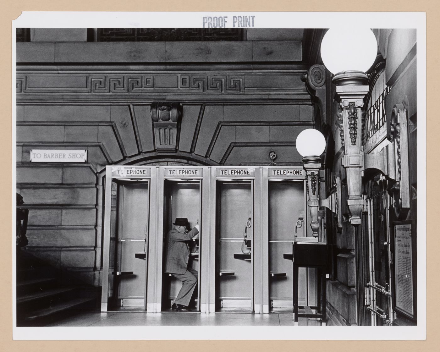 Interior view of the Lackawanna Railroad Terminal showing telephone booths and a man, Hoboken