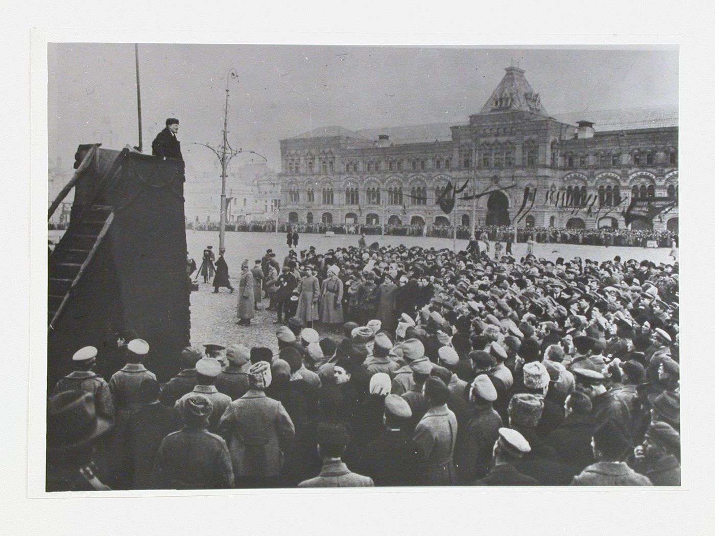 View of a meeting in Red Square showing Lenin addressing a group of soldiers from a podium with the Upper Shopping Arcades in the background, Moscow