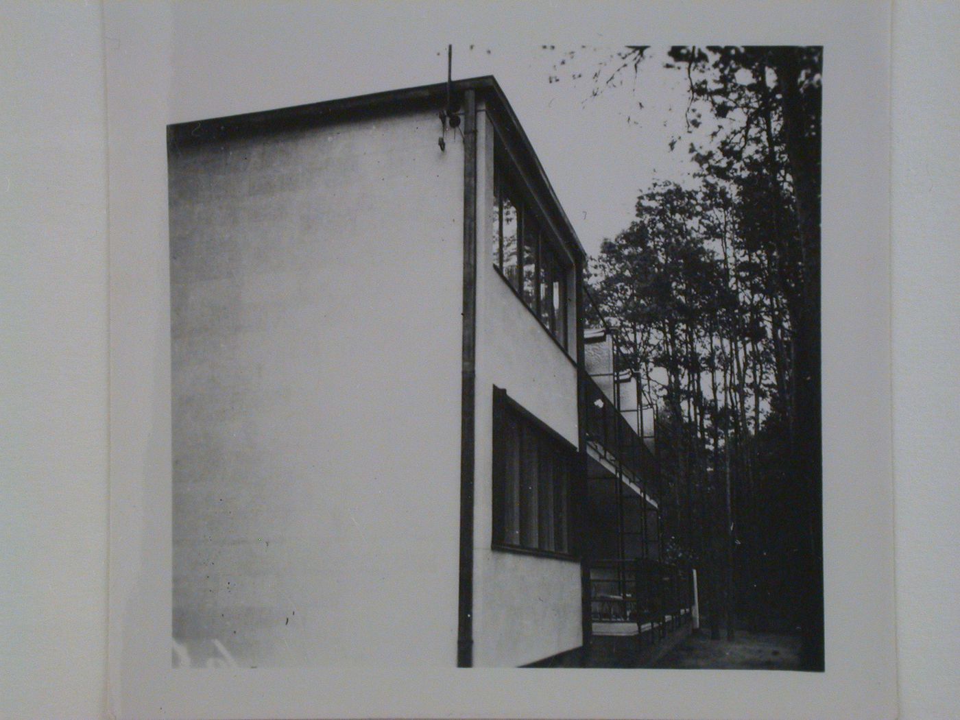 View of the lateral façade of a two-storey apartment building on a wooded site