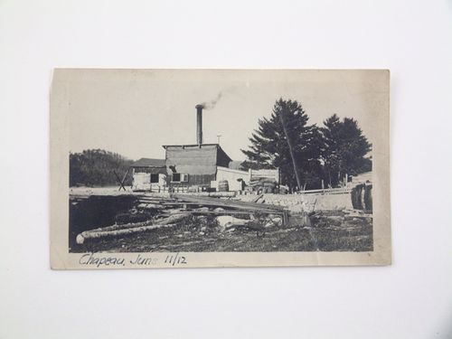 View of construction materials at the back of industrial workshop with chimney, Chapeau, Québec, Canada