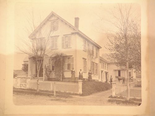 Wooden house with lattice porch, six standing figures and a horse and buggy
