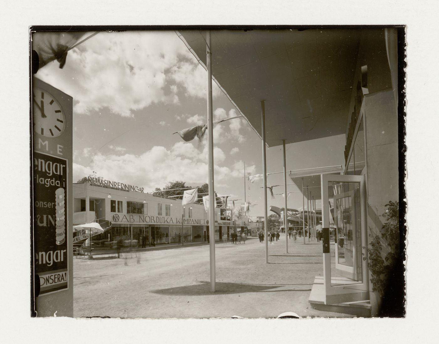 View of the principal façade of hall 8 at the Stockholm Exhibition of 1930 showing a covered walkway with an advertising post in the foreground, Stockholm