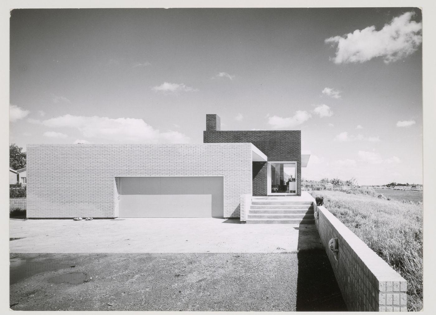 Exterior view of Van den Doel House showing the garage door and retaining wall, Ilpendam, Netherlands