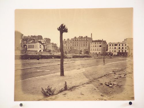 View of a street showing buildings and a branchless tree in the foreground after the Paris Commune uprising of 1871, Paris, France