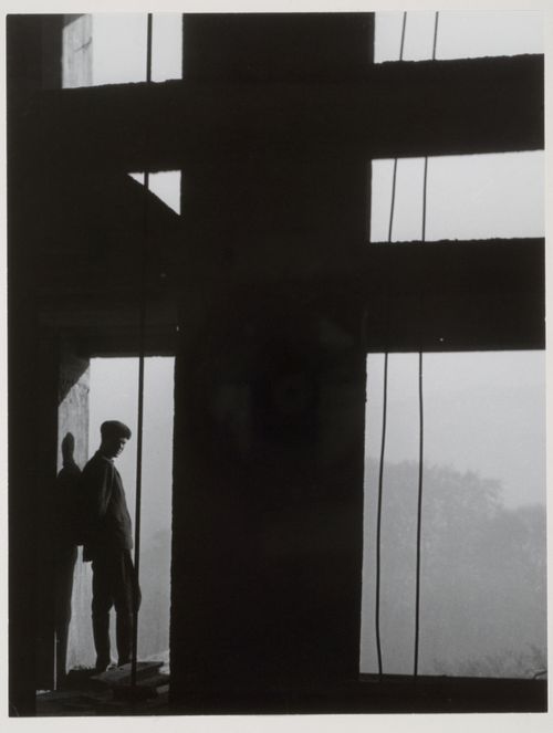 Interior view of Unité d'habitation under construction showing a worker standing within the reinforced concrete structural frame, Marseille, France