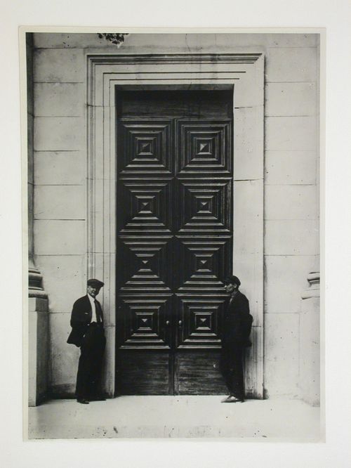 Exterior view of an apartment building showing an entrance door and two men in the foreground, 16 Mokhovaia Street, Moscow
