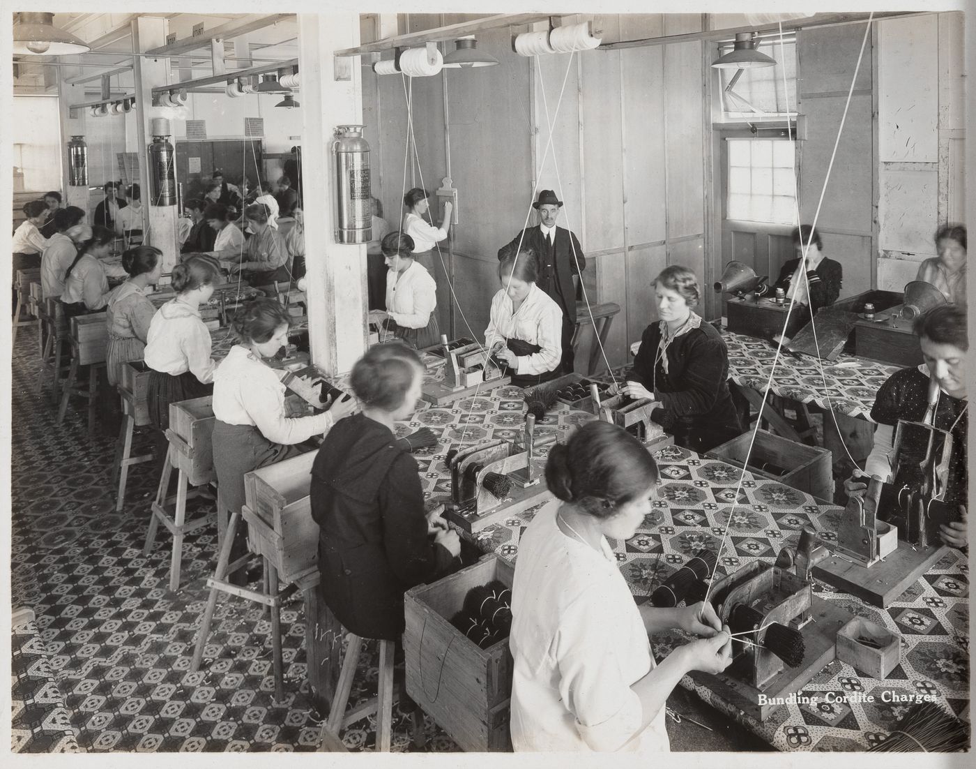 Interior view of workers bundling cordite charges at the Energite Explosives Plant No. 3, the Shell Loading Plant, Renfrew, Ontario, Canada