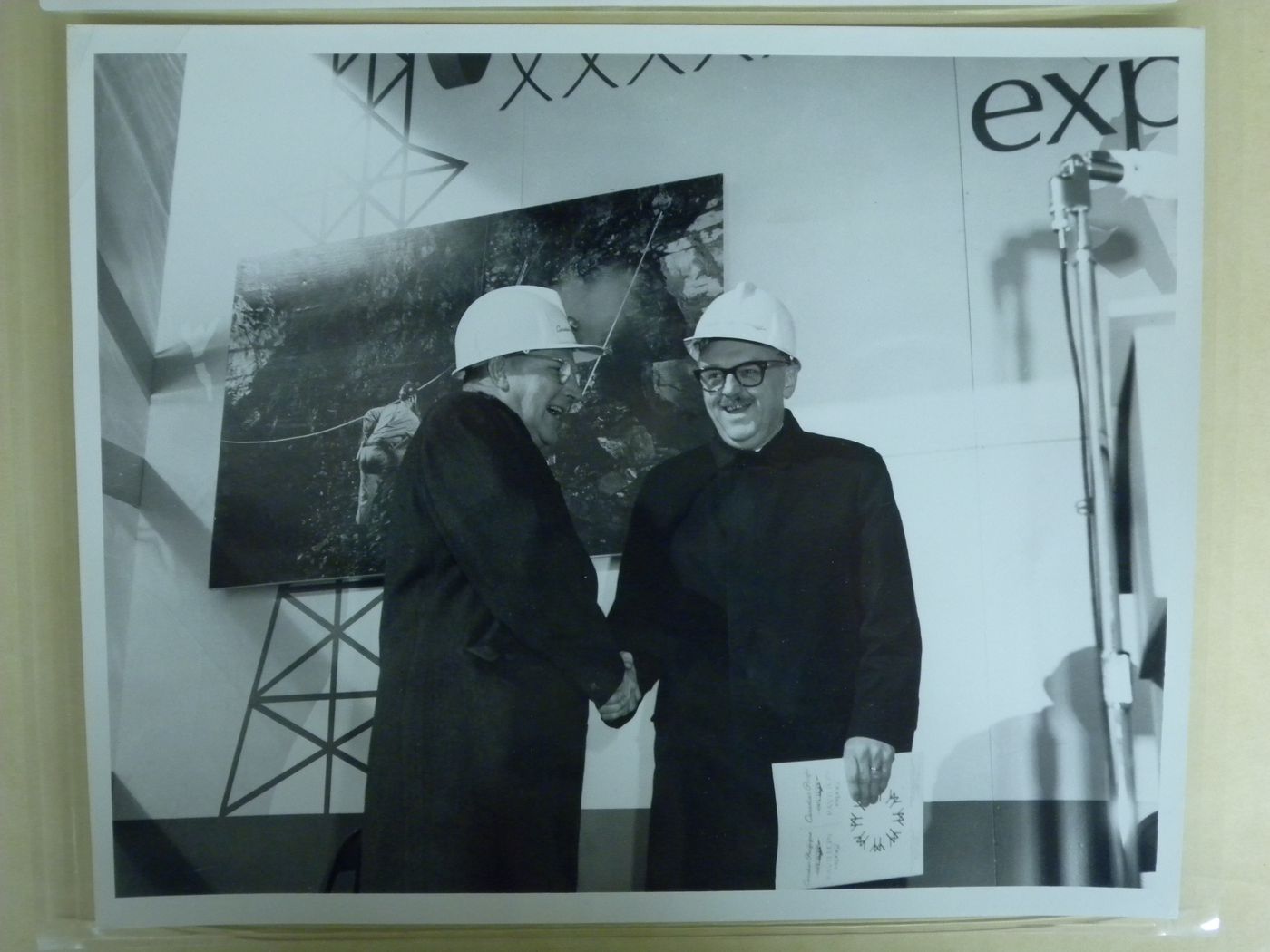 Portrait of Montréal Mayor Jean Drapeau shaking hands with an unidentified man at the Canadian Pacific-Cominco Pavilion, Expo 67, Montréal, Québec