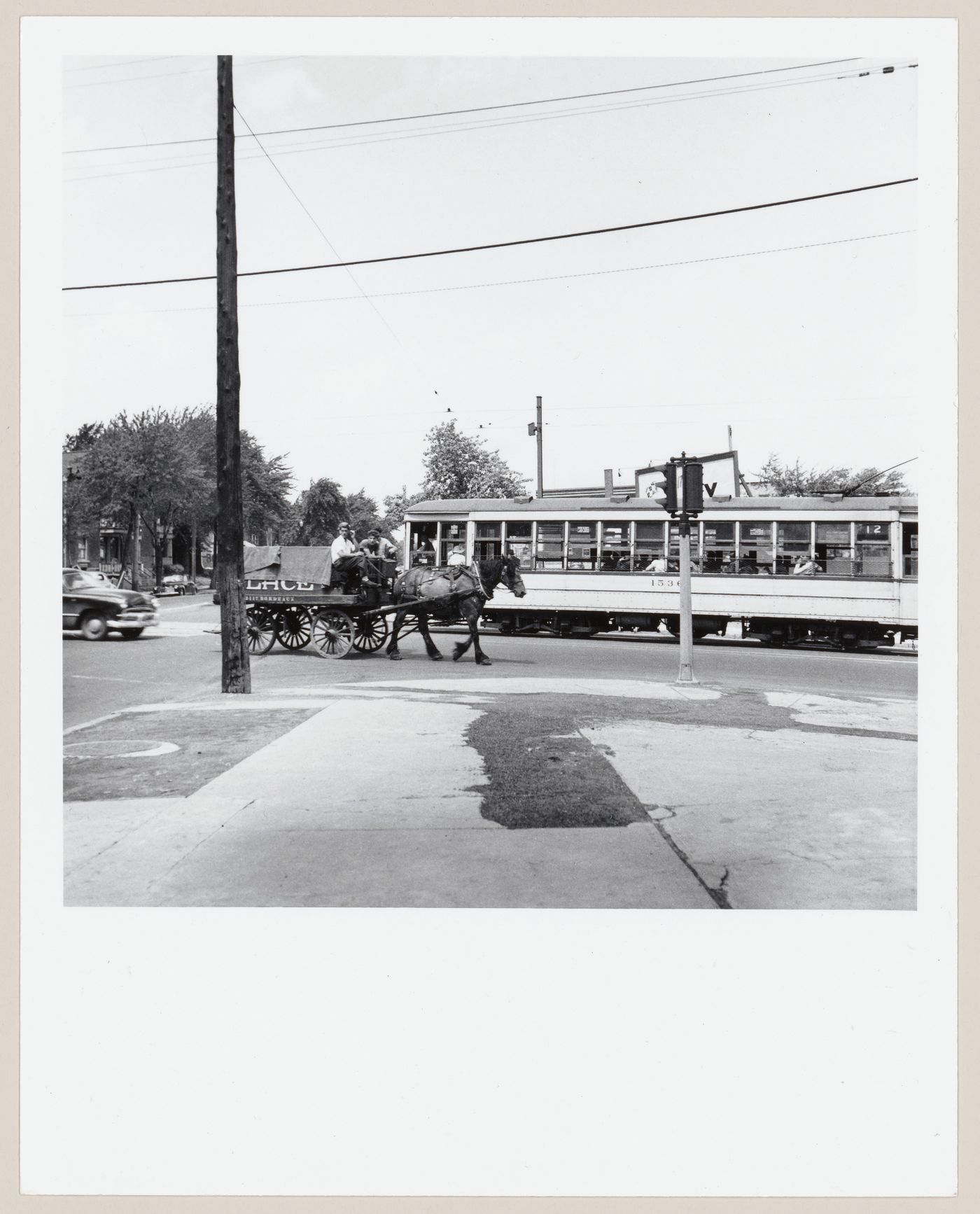 Tramway et  voiture hippomobile d'un vendeur de glace se croisant à une intersection, Montréal, Québec