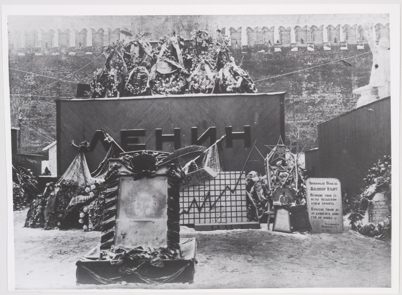 View of the first wooden Lenin Mausoleum showing wreaths, flower arrangements, banners, and a tomb slab, Red Square, Moscow