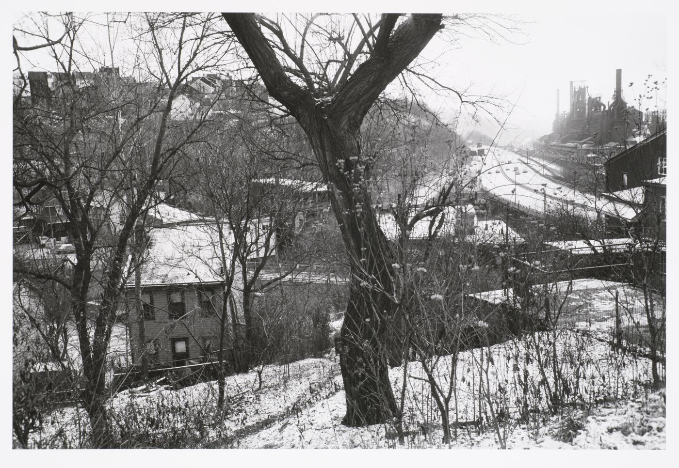 View on a hill overlooking houses, highway, and steel mill in snow, on right, Pittsburgh, Pennsylvania