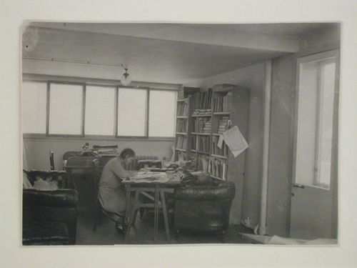 Interior view of Moisei Ginzburg's studio in the People's Commissariat for Finance (Narkomfin) Apartment Building showing a woman seated at a desk, 25 Novinskii Boulevard, Moscow