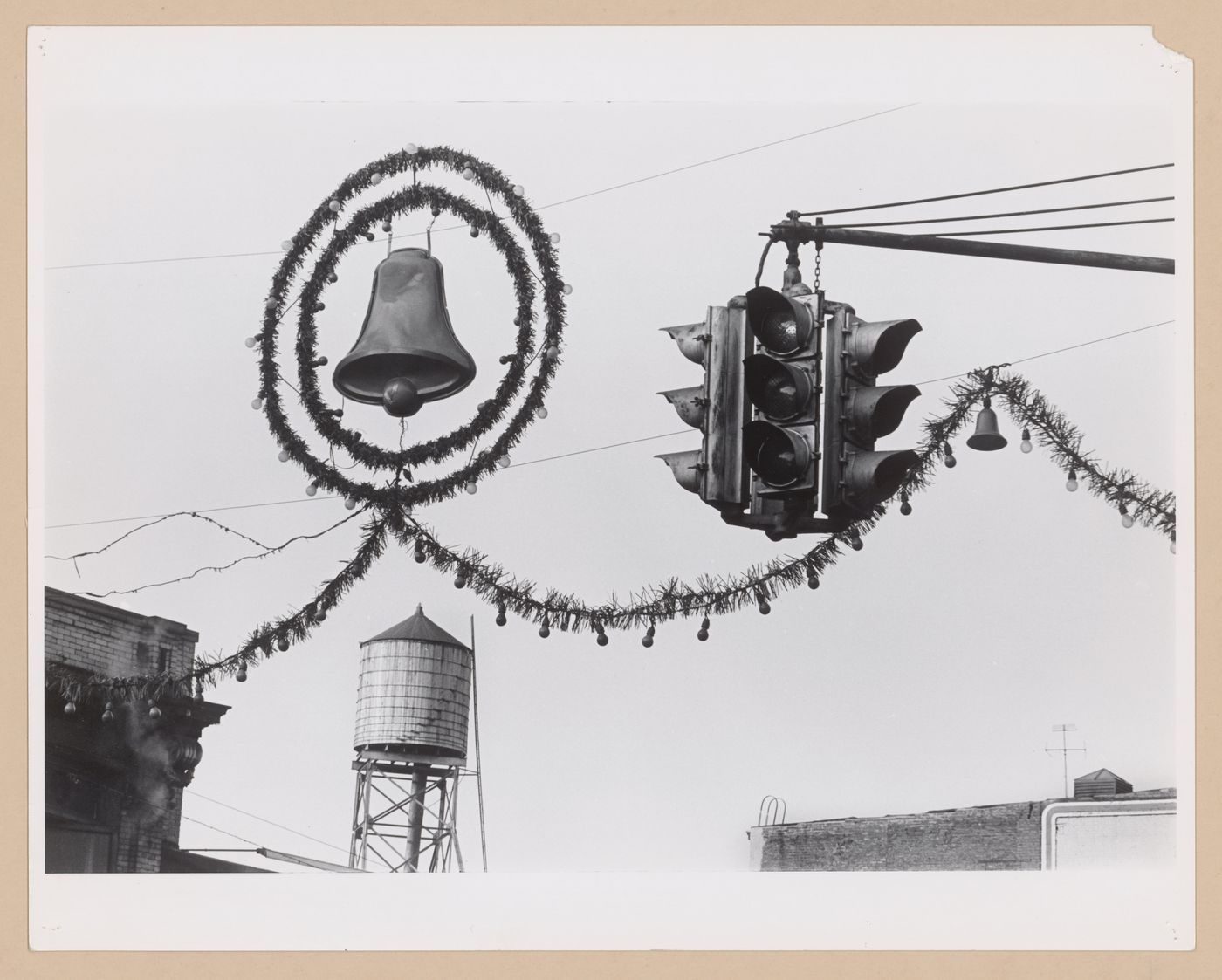 View of street decorations, including a bell, wreath, lights and garland, showing traffic signals with a water tower in the background, Hoboken, United States