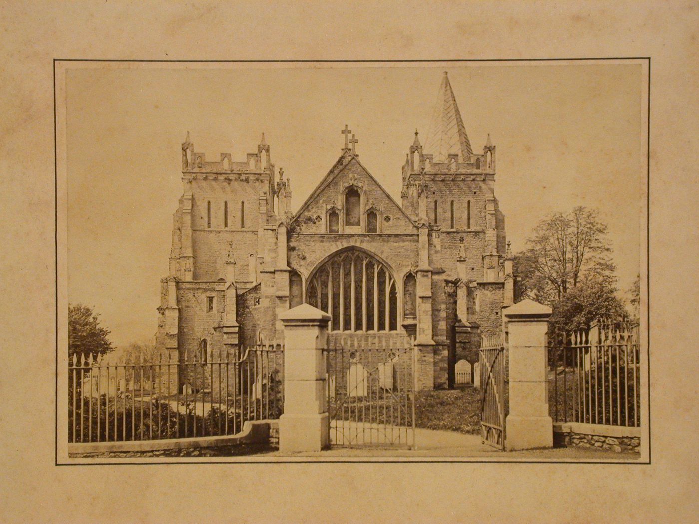 View through the fence and gateway of a churchyard showing the church and cemetery, England