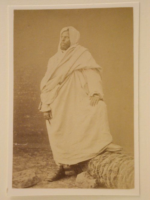 Standing white robed man with foot on rock