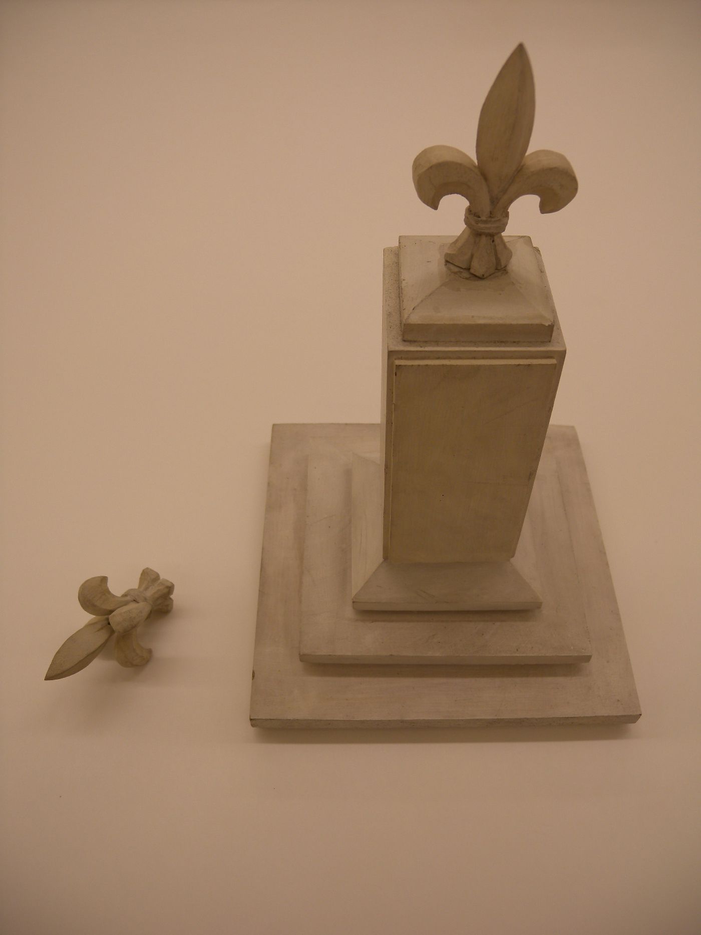 Une colonne sur une base avec 2 fleurs de lys
