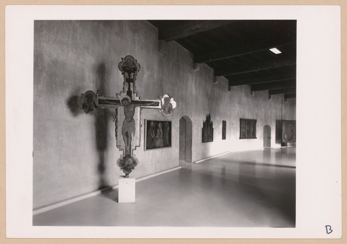Interior view of a gallery showing a freestanding painted crucifix and paintings, Museo di Castelvecchio, Verona, Italy