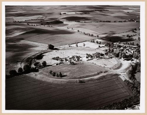 Partial aerial view of Avebury showing houses and roads enclosed by a henge and with Silbury Hill in the distance, Avebury, Wilthire, England