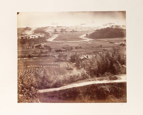 View of a horse racetrack showing farmland and a farm in the foreground and part of the foreign settlement in the background, Kobe, Japan