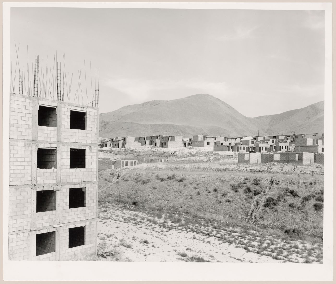 View of an industrial park under construction with a partially completed building in the foreground and partially completed houses and mountains in the background, Mesa de Otay, Tijuana, Baja California, Mexico