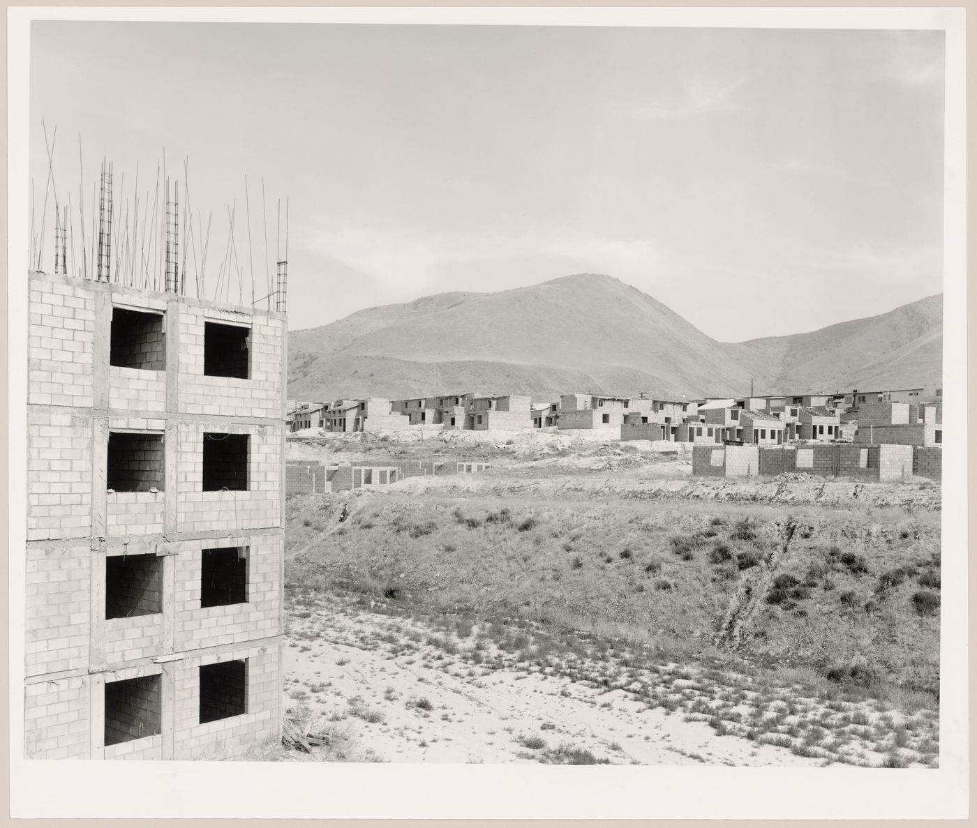 View of an industrial park under construction with a partially completed building in the foreground and partially completed houses and mountains in the background, Mesa de Otay, Tijuana, Baja California, Mexico