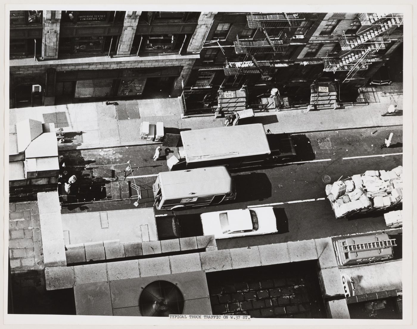 Aerial view of West 37th Street showing an automobile, trucks, people and buildings, Manhattan, New York City, New York