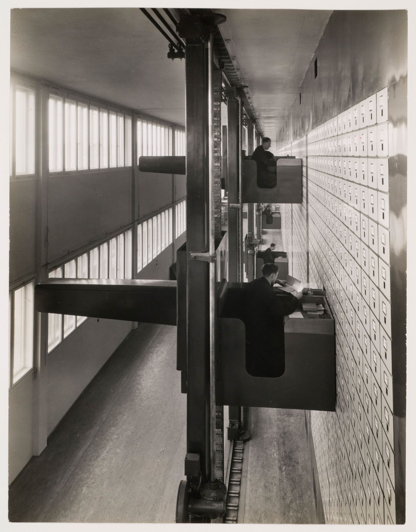 Interior view of the Central Social Insurance Institution showing men working in mobile work stations used to access the card catalog drawers, Prague, Czechoslovakia (now Czech Republic)