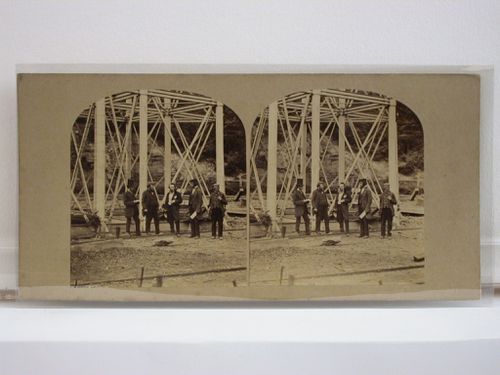 Stereograph of five men standing at the base of one of the structural piers of the Crumlin Viaduct while under construction, Monmouthshire (now in Gwent County), Wales