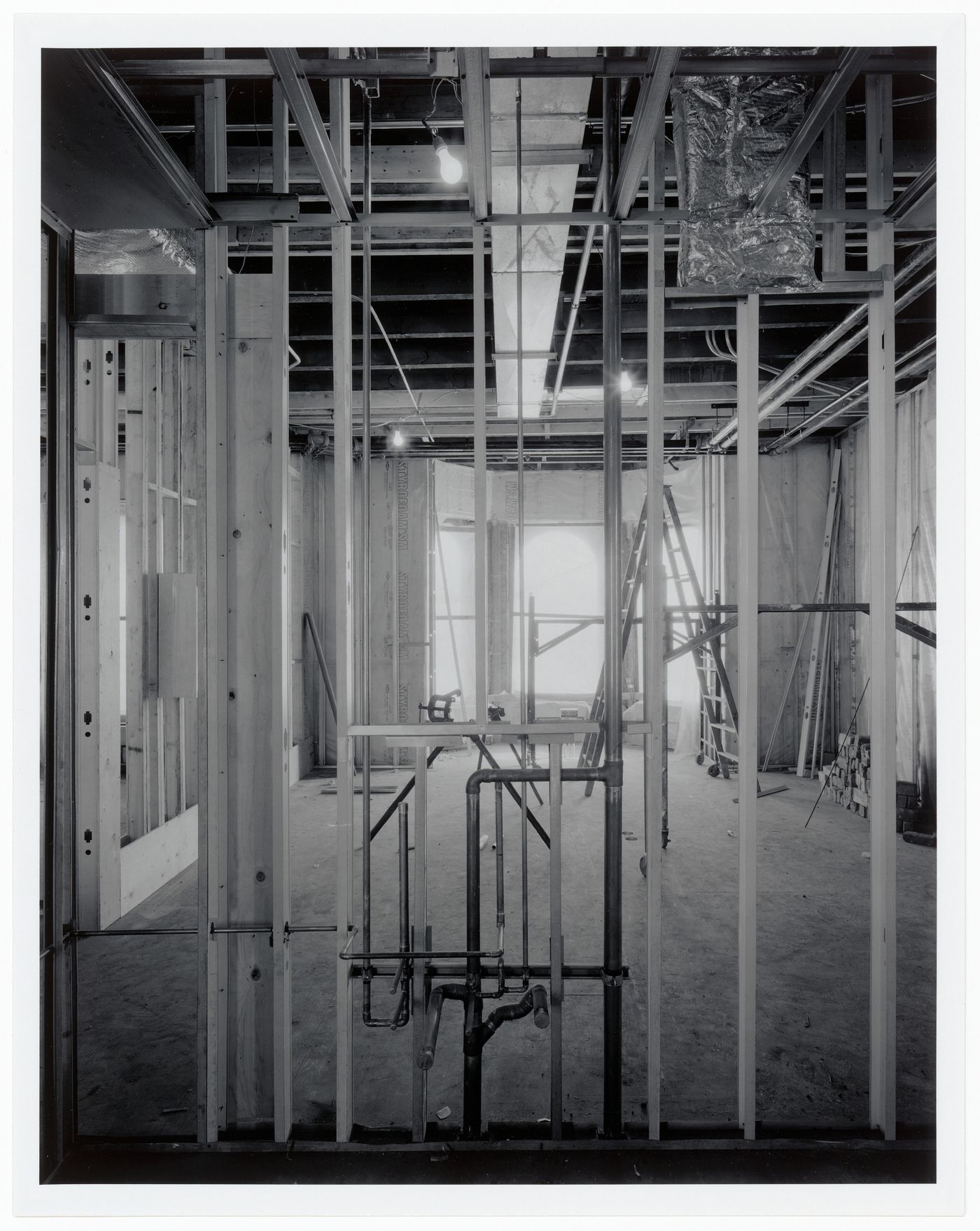 Interior view of a room showing open structural framework and plumbing pipes, Shaughnessy House under renovation, Montréal, Québec