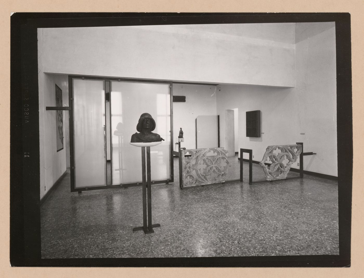Interior view of a gallery showing a bust on a pedestal and fragments of stone tracery, Museo Correr, Venice, Italy